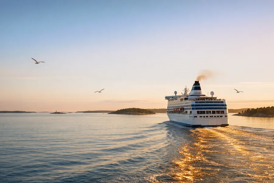Passagerarfärja på väg ut ur en hamn i kvällssol